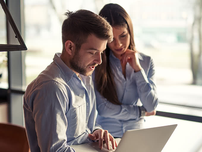 Man holding laptop with colleague